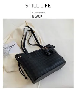 Détail d'un sac cabas noir à motif damier avec une breloque en forme de petit chien