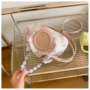Detail of fabric bucket bag with pink butterfly prints and white beaded handle