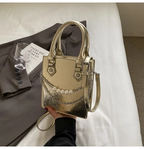 Gros plan d'un sac à main doré effet miroir avec chaîne en perles et fine bandoulière