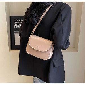 Dettaglio della borsa a tracolla in pelle rosa polvere con scritte dorate e design minimal