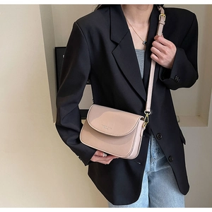 Dettaglio di una borsa a tracolla rosa cipria abbinata a un elegante blazer nero