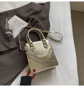 Détail du petit sac doré métallisé avec chaîne élégante et ornements en perles