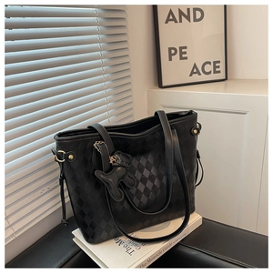 Détail du sac cabas matelassé noir avec pendentif ours en cuir sur un bureau élégant