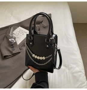 Détail du sac à bandoulière noir avec texture vintage, perles et chaîne argentée