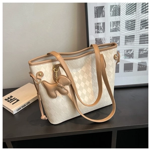 Détail du sac fourre-tout matelassé blanc cassé avec anses brunes et breloque chien