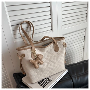 Détail du sac cabas à damier tissé avec anses en cuir et charm animalier élégant