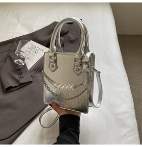 Détail du mini sac argenté texturé avec chaînes superposées de perles et de métal brillant