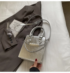 Détail du sac argenté métallisé avec chaîne en perles blanches et maillons rétro