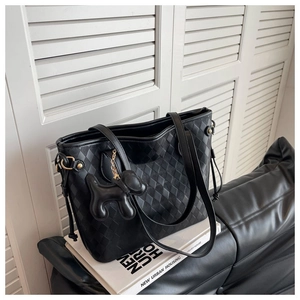 Détail du sac cabas matelassé noir avec charm chien en cuir sur un livre de design