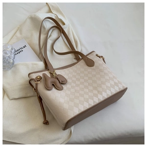 Détail d'un sac cabas à carreaux avec anses en cuir marron et pendentif chien mignon