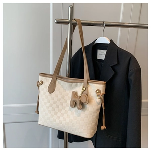 Détail du sac cabas à damier avec anses en cuir marron et pendentif chiot mignon