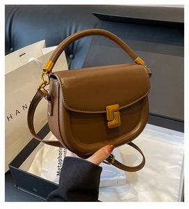 Dettaglio della borsa a sella in pelle marrone vintage con fibbia dorata a forma di S unica