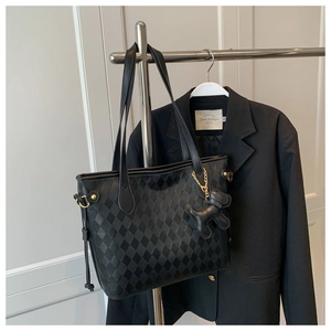 Détail du sac cabas noir matelassé avec motif à losanges et breloque en forme de chien