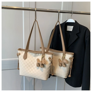Détail du sac cabas beige matelassé avec poignées en cuir marron et breloque chiot