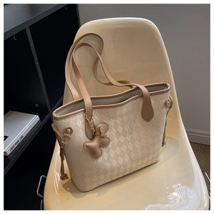 Vue détaillée du sac cabas matelassé beige avec bordure marron sur une chaise