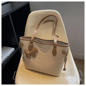 Détail du cabas matelassé beige avec poignées en cuir marron et pendentif petit chien
