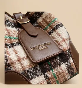 Detail of vintage plaid texture and leather tag with golden buckle on bucket bag