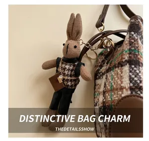 Detail of a brown knitted rabbit charm with houndstooth vest and metal chain bag