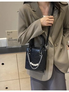 Sac bandoulière chic en cuir noir avec chaîne de perles et détails de maillons argentés