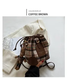 Brown checkered bucket bag with leather strap and cute rabbit pendant on a blazer
