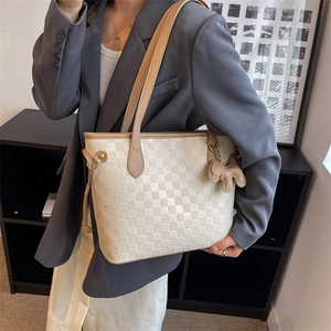 Sac fourre-tout beige avec gaufrage en damier et pendentif animal porté sur veste