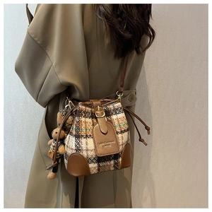 Detail of plaid bucket bag with leather trim and cute teddy bear charm accessory