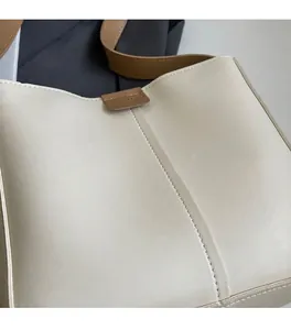 Detail showing the cream faux leather texture with brown strap and visible stitching