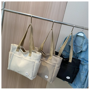 Drei minimalistische Canvas-Tragetaschen in Weiß, Khaki und Schwarz mit Außentaschen