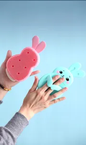 Detail of rabbit-shaped silicone cleaning brush with finger ring handle in two colors