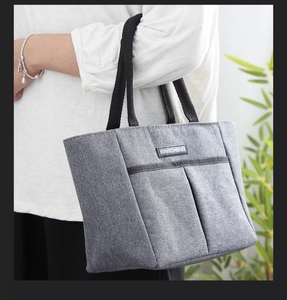 Détail du sac isotherme gris avec poignées en nylon noir et étiquette en cuir