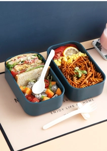 Detail of double-layer lunch box compartments with pasta salad and creative cutlery set