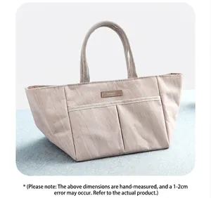 Dettaglio della borsa termica con tasche frontali ed elegante patch logo in pelle marrone
