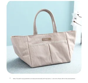 Close-up of insulated lunch bag with front pockets and elegant brown leather logo detail