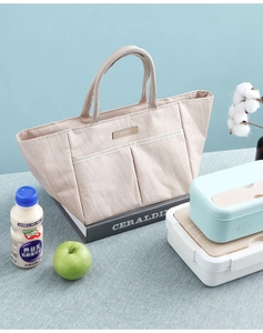 Close-up of beige canvas lunch bag featuring two front pockets and durable fabric texture