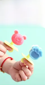 Detail showing cartoon bear and cat paw popsicle molds with yellow handles in a handheld view