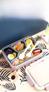 5-compartment pink stainless steel lunch box with cutlery set in a cozy dining setting