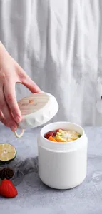 Close-up of white breakfast soup cup with wood grain lid and silicone handle details