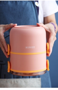 Detailopname van roze ronde lunchbox met oranje gespen en een heldere bruine onderkant
