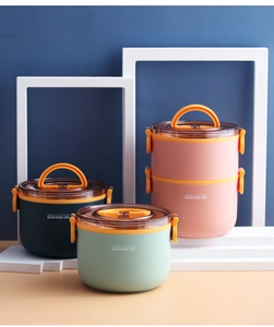 Detail van meerlaagse lunchboxen met oranje handgrepen en kliksluitingen deksels
