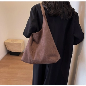 Detailed back view of a large brown suede tote bag worn by a model for a minimalist look