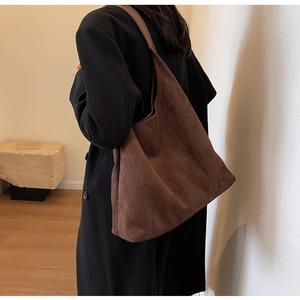 Macro shot of large dark brown suede tote bag on shoulder with smooth leather texture