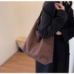 Detail view of large brown faux suede hobo bag styled on shoulder with minimalist texture