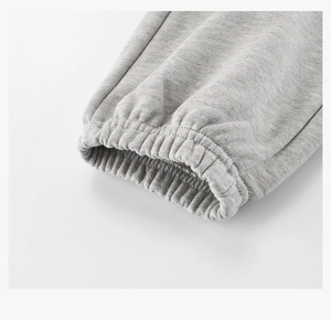 Détail macro du tricot gris montrant les poignets élastiques des pantalons de sport