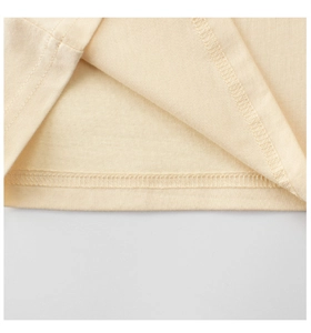 Détail de couture à double aiguille sur l'ourlet du t-shirt en coton beige pour enfant