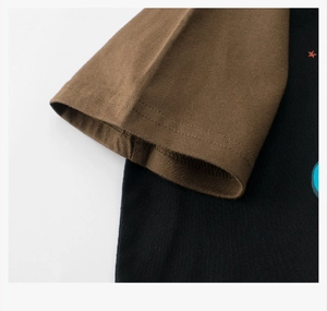 Detail of raglan sleeves on a boys' cotton T-shirt featuring contrast stitching and prints