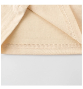 Détail de la double couture sur l'ourlet d'un t-shirt en tricot de coton beige pour fille