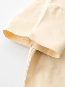 Gros plan d'une manche de t-shirt enfant jaune clair avec détails de couture soignés
