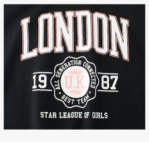 Nahaufnahme des weiß-rosa London 1987 Aufdrucks auf einem schwarzen Baumwoll-T-Shirt