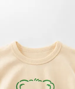 Close-up of ribbed crew neck and fine stitching on a pale yellow cotton t-shirt for kids