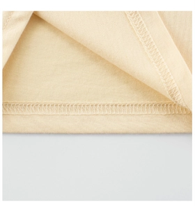 Détail macro de la couture overlock et texture en maille douce sur l'ourlet du t-shirt enfant